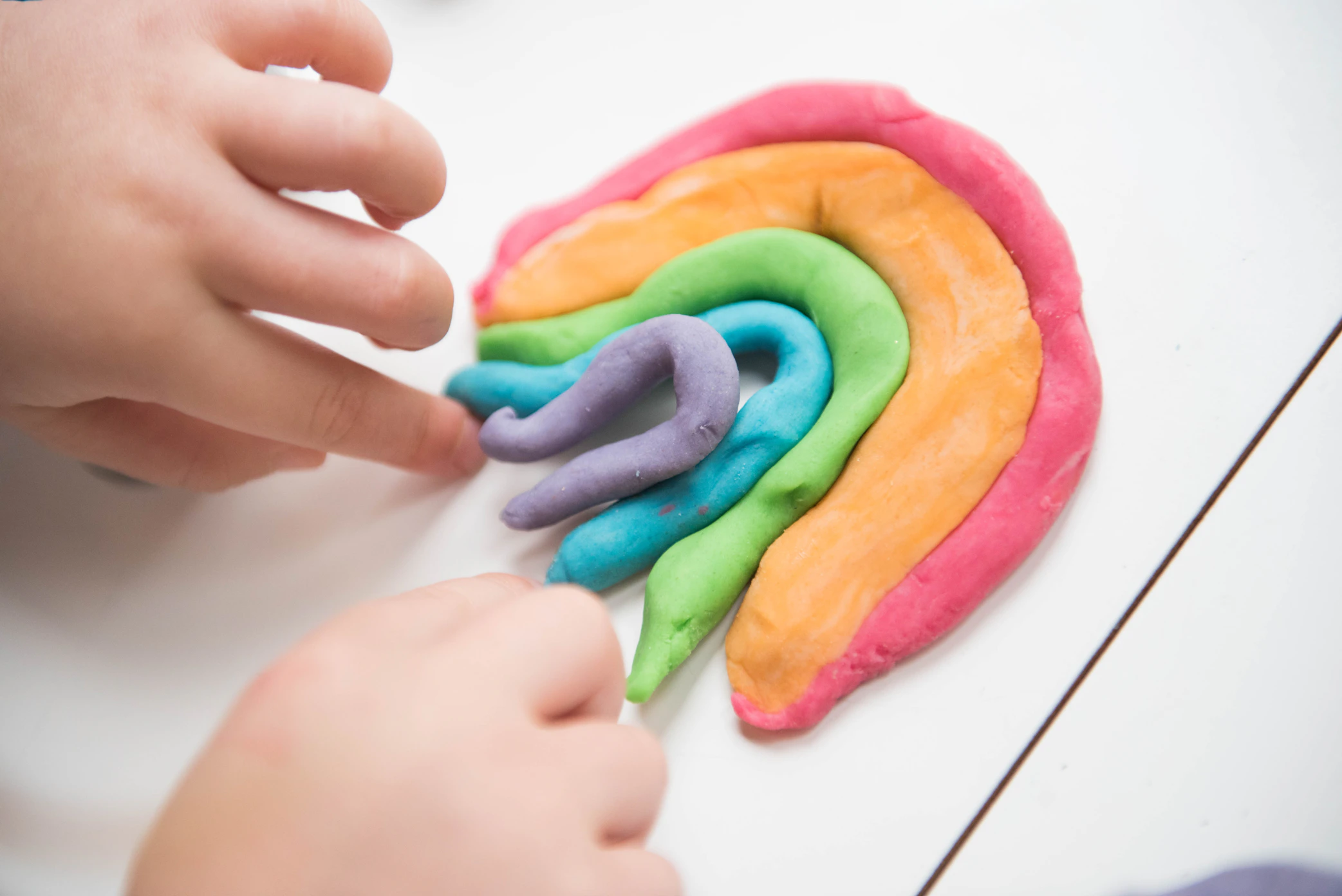 Child's hands building a rainbow out of Playdoh