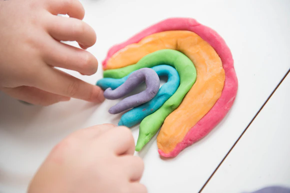 Child's hands building a rainbow out of Playdoh