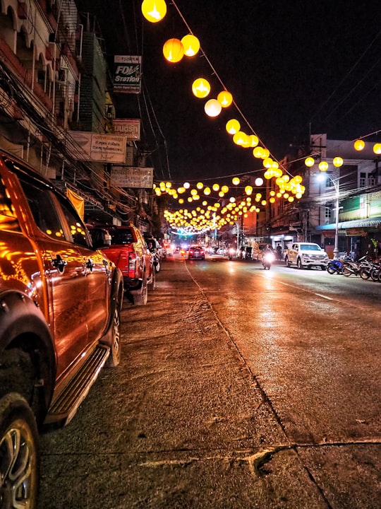 vehicles parked on side of street with turned-on lanterns in Chiang Rai Thailand