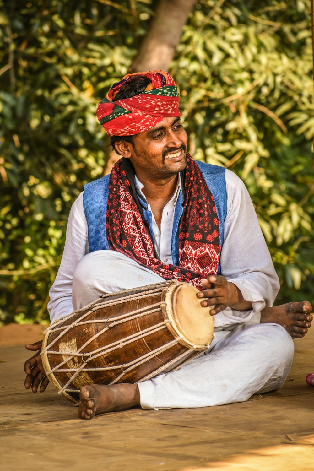 man sitting while holding brown drum