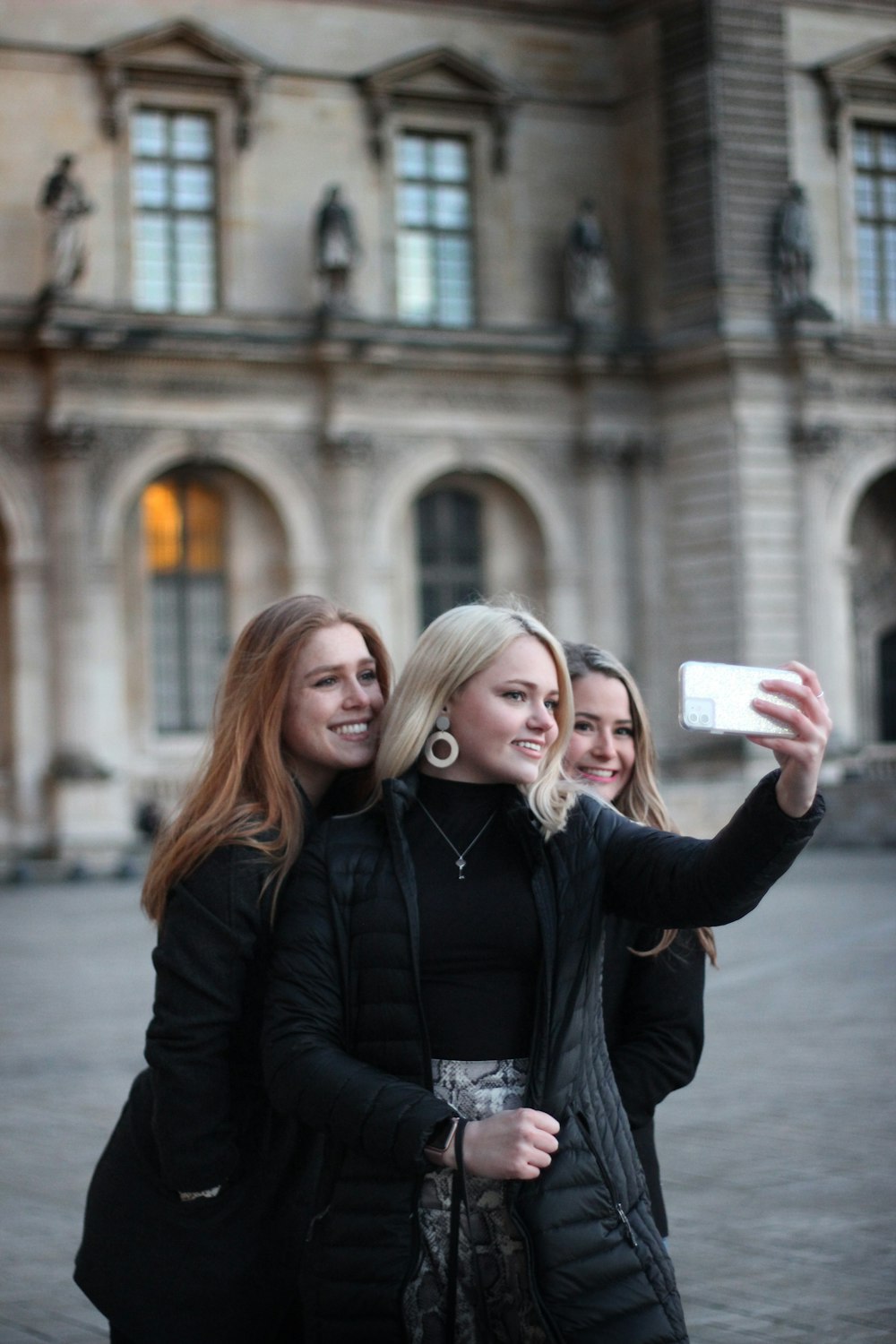 three women standing near brown building