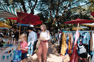 A vibrant, joyful group of travelers exploring a colorful market street under bright sunlight.