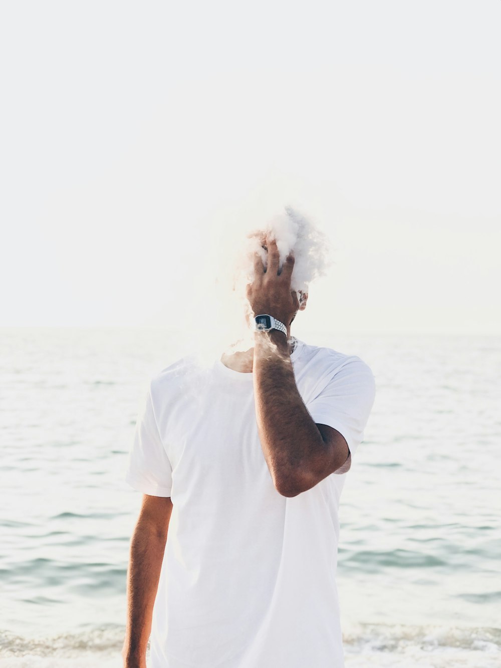 man in white shirt standing near body of water