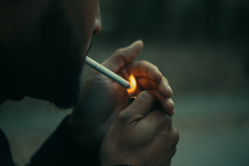 close-up photography of man using cigarette during daytime