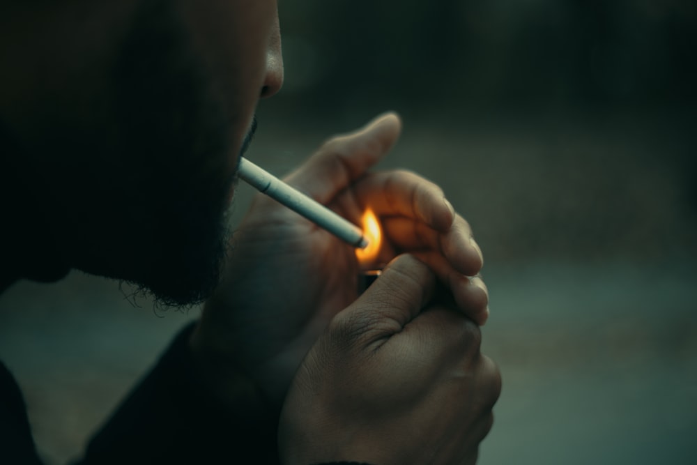 Fotografía de primer plano del hombre que usa el cigarrillo durante el día