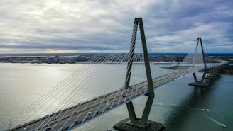 Aerial view of a cable-stayed bridge spanning a wide river, with traffic flowing smoothly.