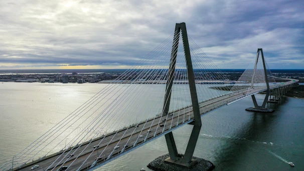 Aerial view of a cable-stayed bridge spanning a wide river, with traffic flowing smoothly.