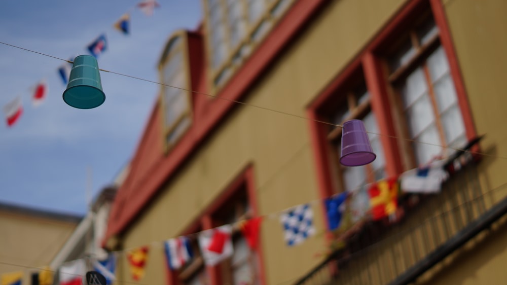 blue and purple disposable cups hanged on cable near houses