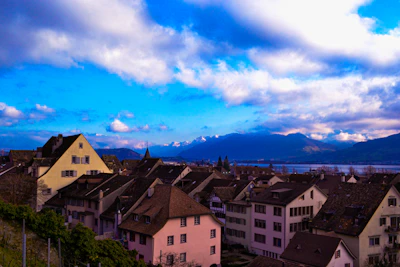 A serene view of Swiss mountains with a traditional village in the foreground at sunrise.