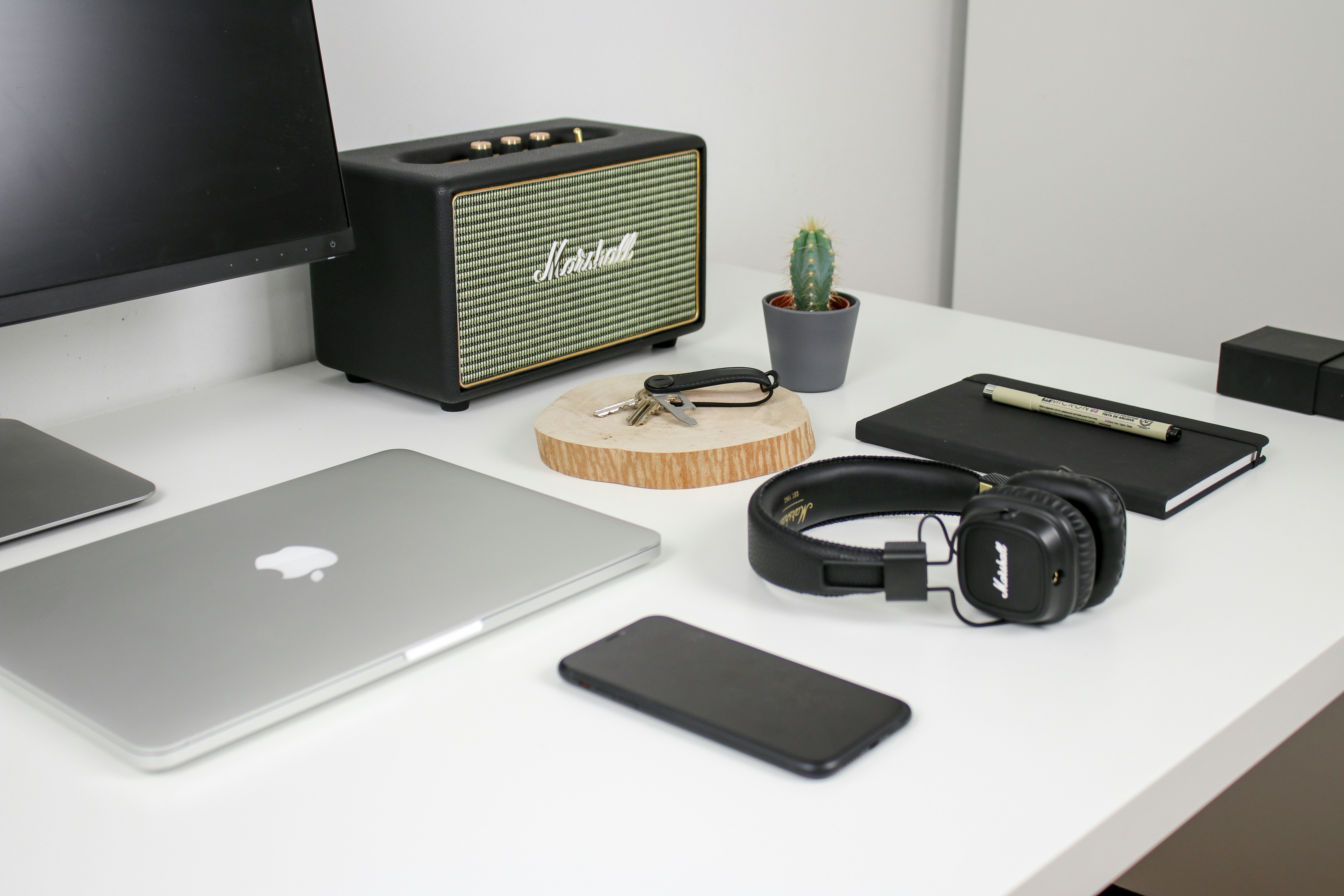 MacBook beside iPhone and headphones on white desk