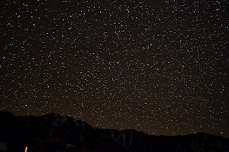 A simple line drawing of mountains beneath a starry sky with delicate scientific icons softly integrated.