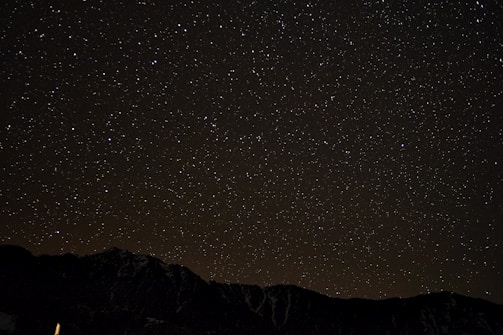 A simple line drawing of mountains beneath a starry sky with delicate scientific icons softly integrated.