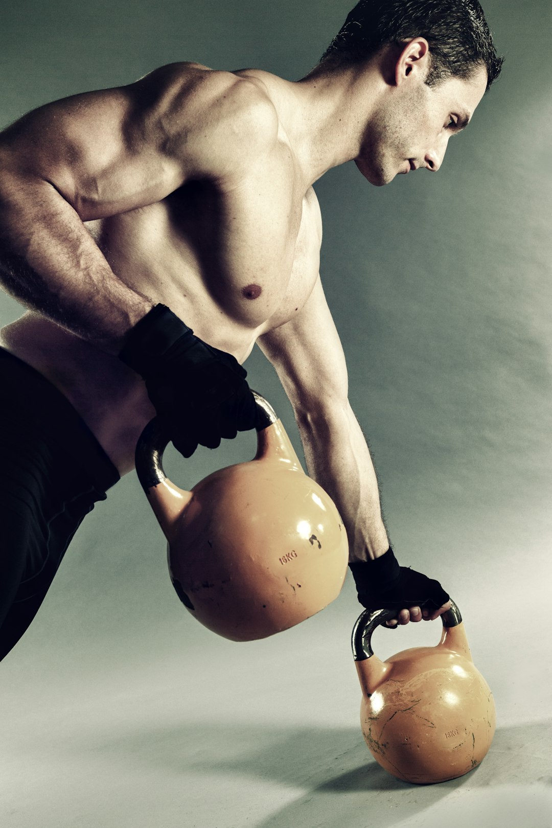 man holding pair of yellow-and-black kettlebells