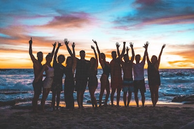 people raising arms on beach