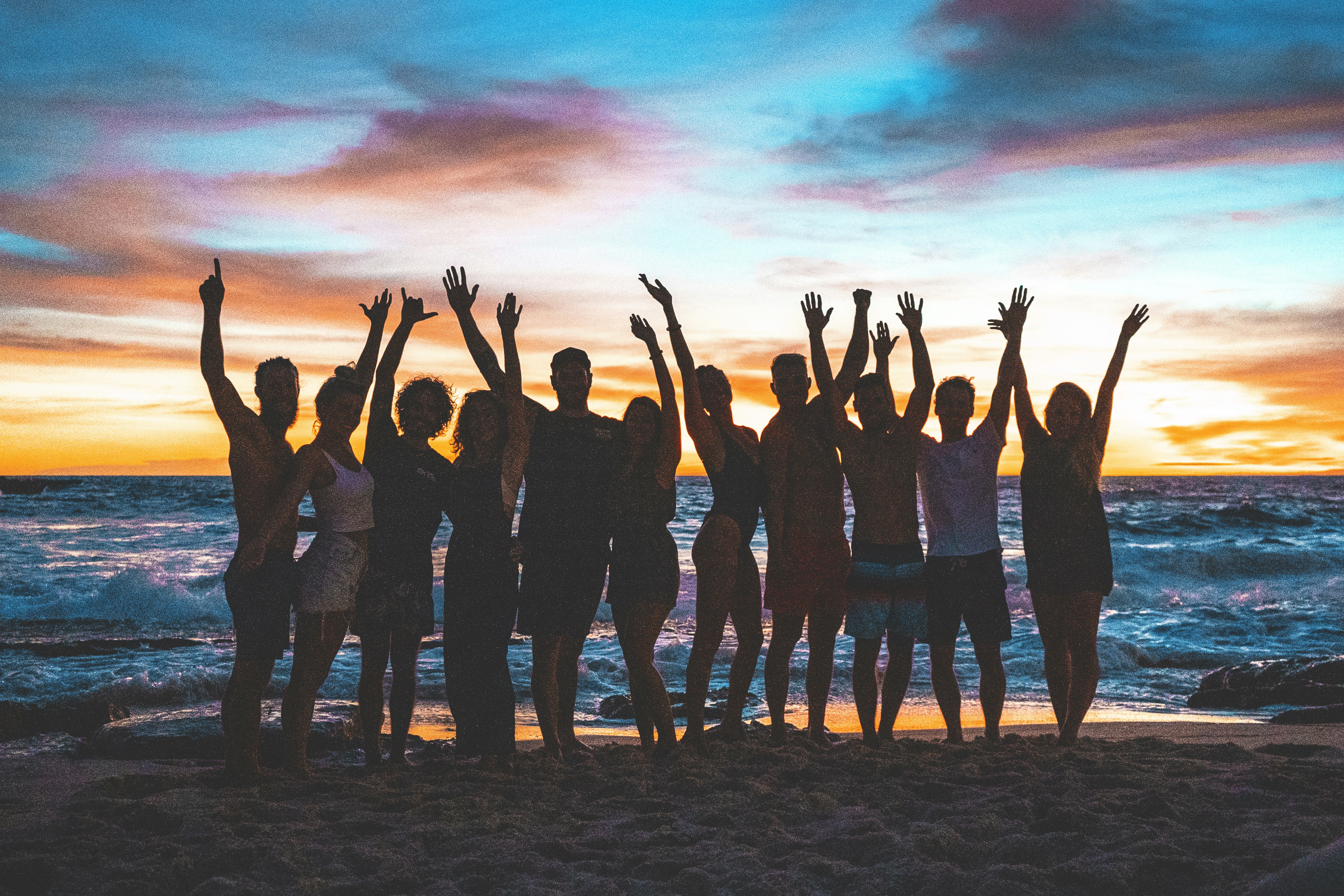 people raising arms on beach