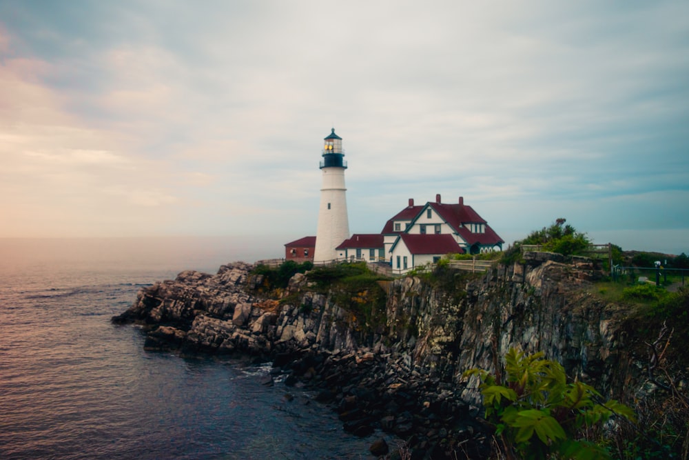 red and white lighthouse on mountain cliff