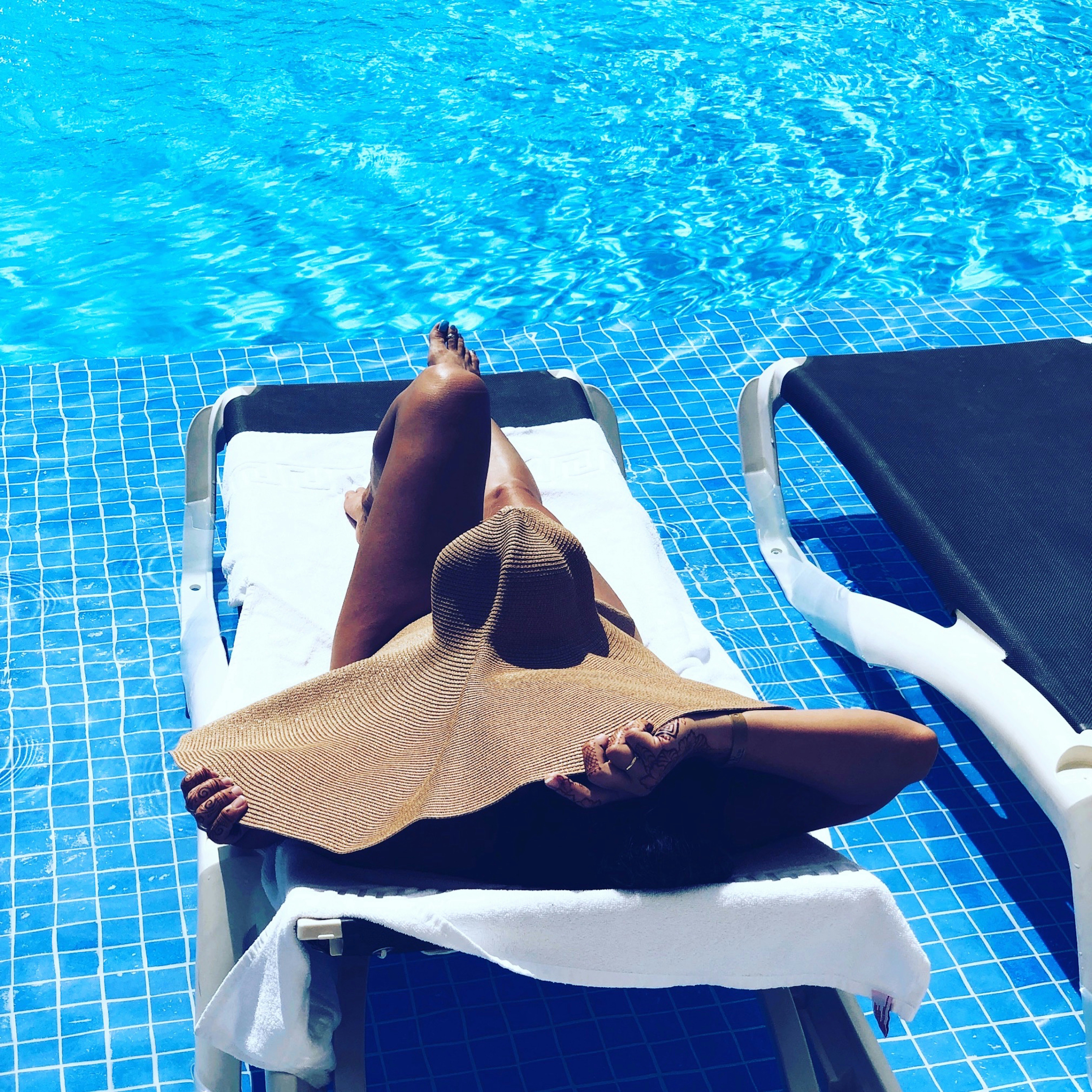 woman lying on the sun lounger in front of swimming pool