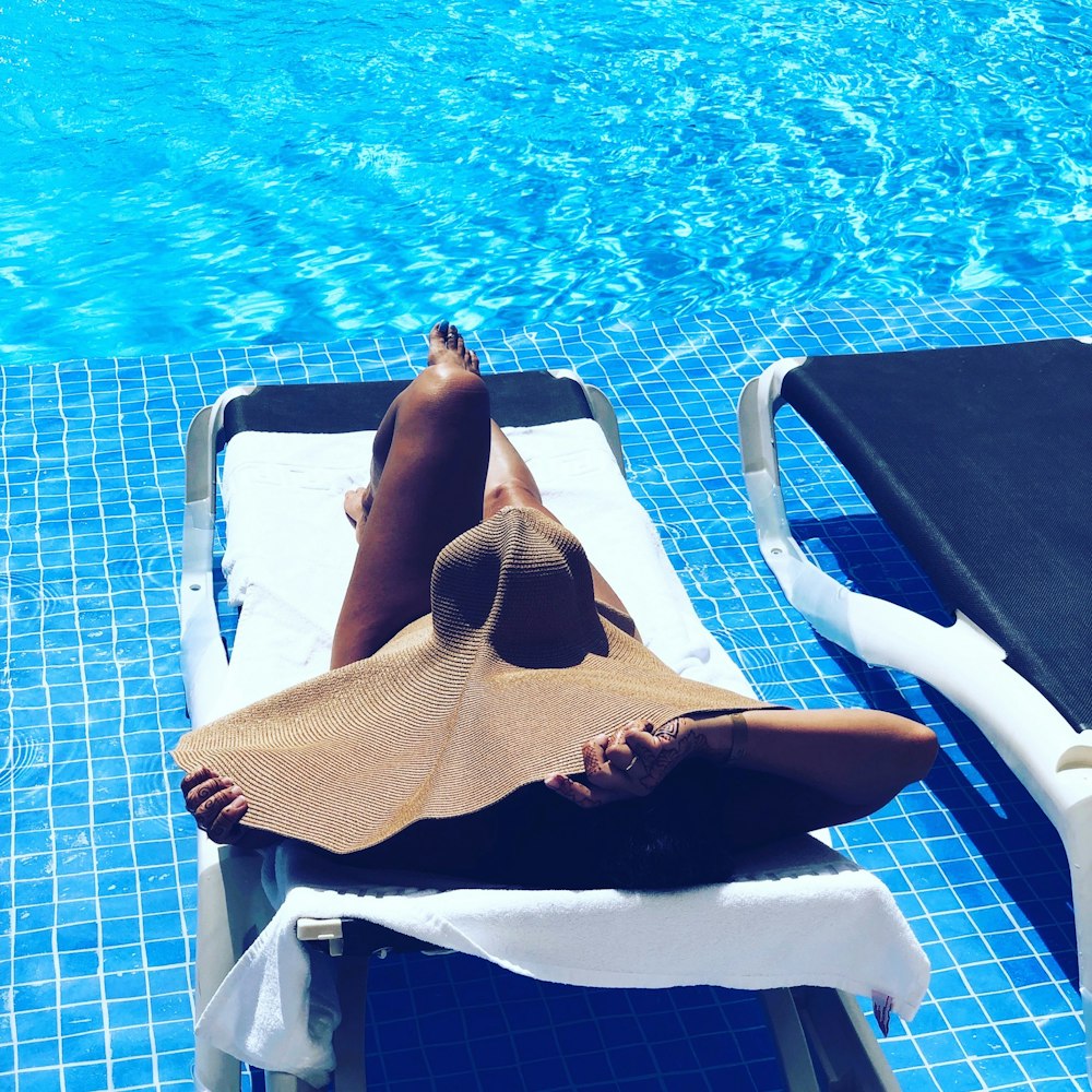 femme allongée sur la chaise longue devant la piscine