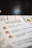 A close-up view of a menu with the heading 'Buck a Shuck PEI Oysters' printed in bold text. Below the heading, descriptions of various oyster offerings are listed, with some small, circular illustrations resembling oysters next to the text. The background appears soft and blurred, with a dark surface at the top portion of the image.