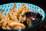 A colorful bowl of crispy fries sprinkled with herbs and served with ketchup.