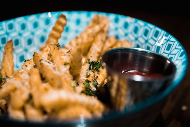 Crispy golden fries sprinkled with seasoning, served in a red branded emo fast food container
