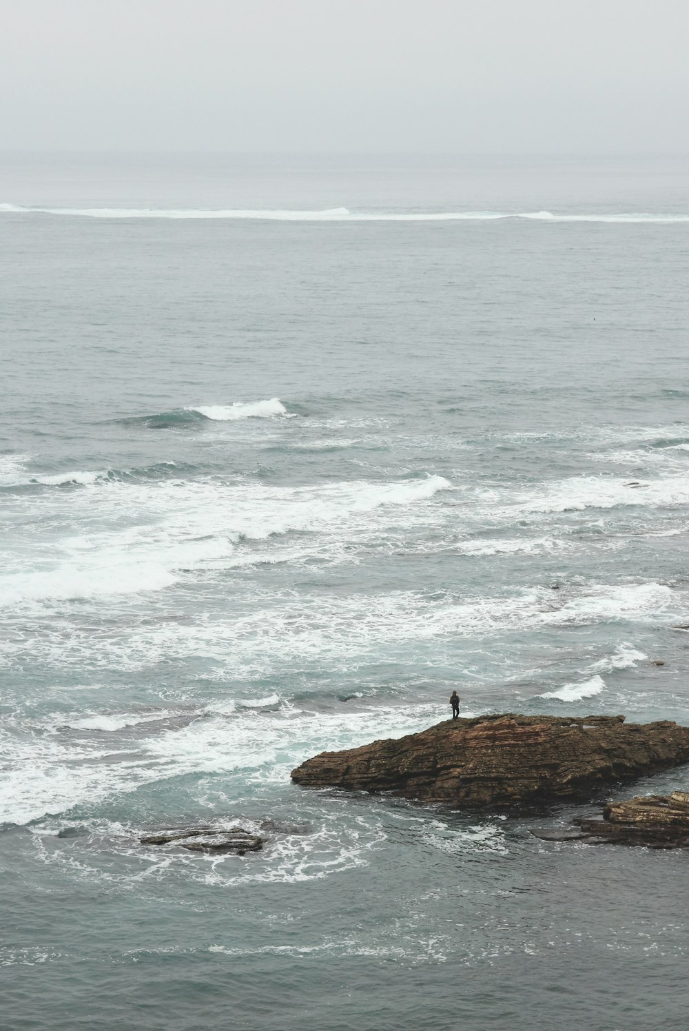 person standing on rock formation near seashore