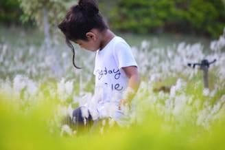 A child observing butterflies in a flower field.