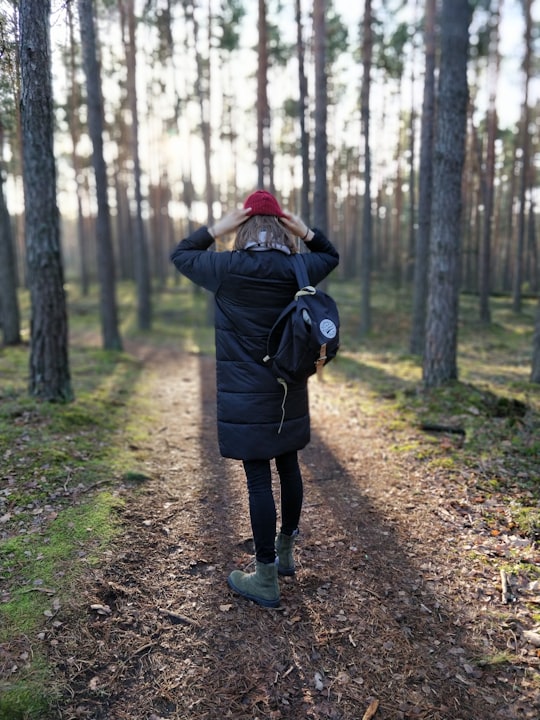 woman in black bubble jacket standing in forest in Kampinos Forest Poland