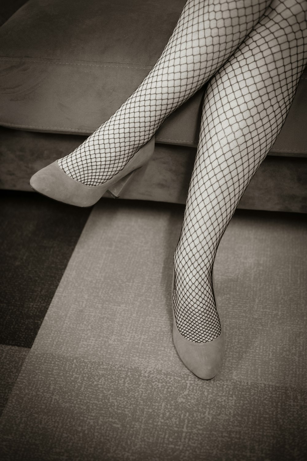 uma foto em preto e branco das pernas de uma mulher com meias de rede de peixe