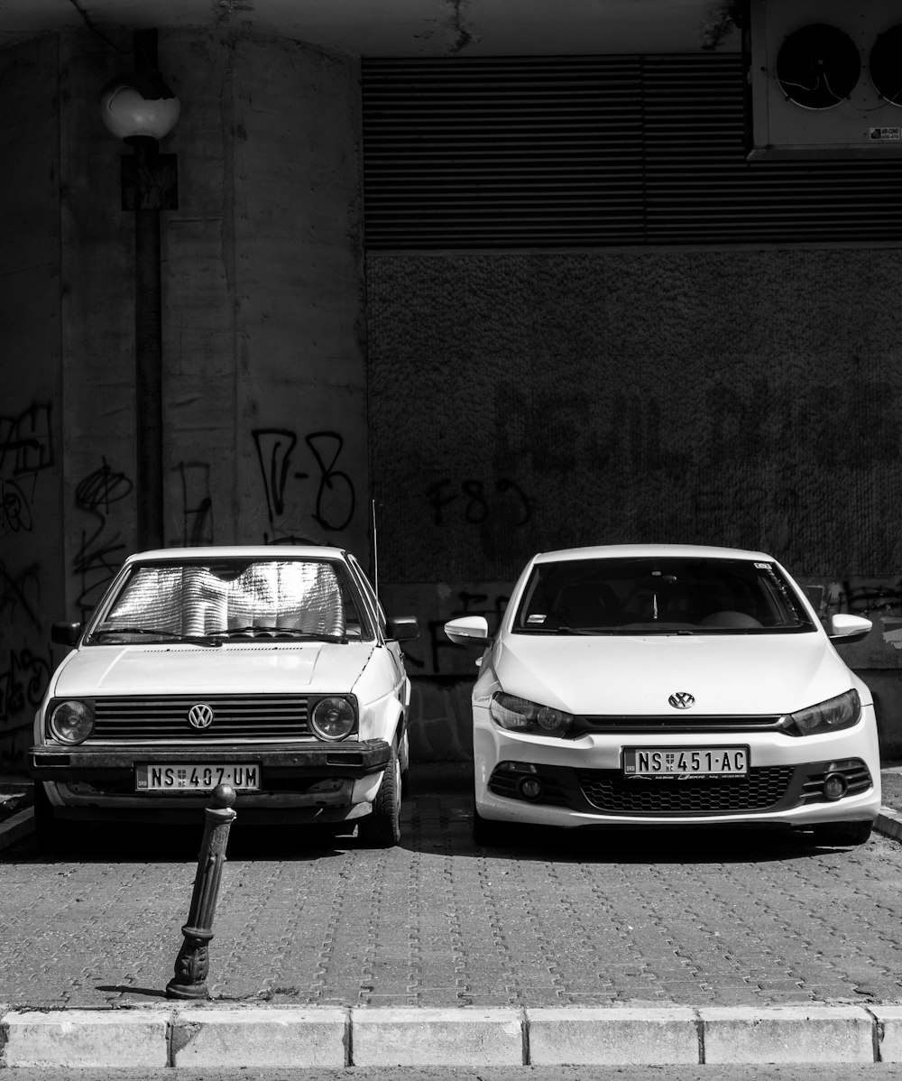 foto in scala di grigi di due auto Volkswagen parcheggiate sul marciapiede