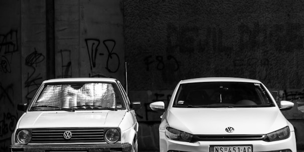 grayscale photo of two Volkswagen cars parked on sidewalk