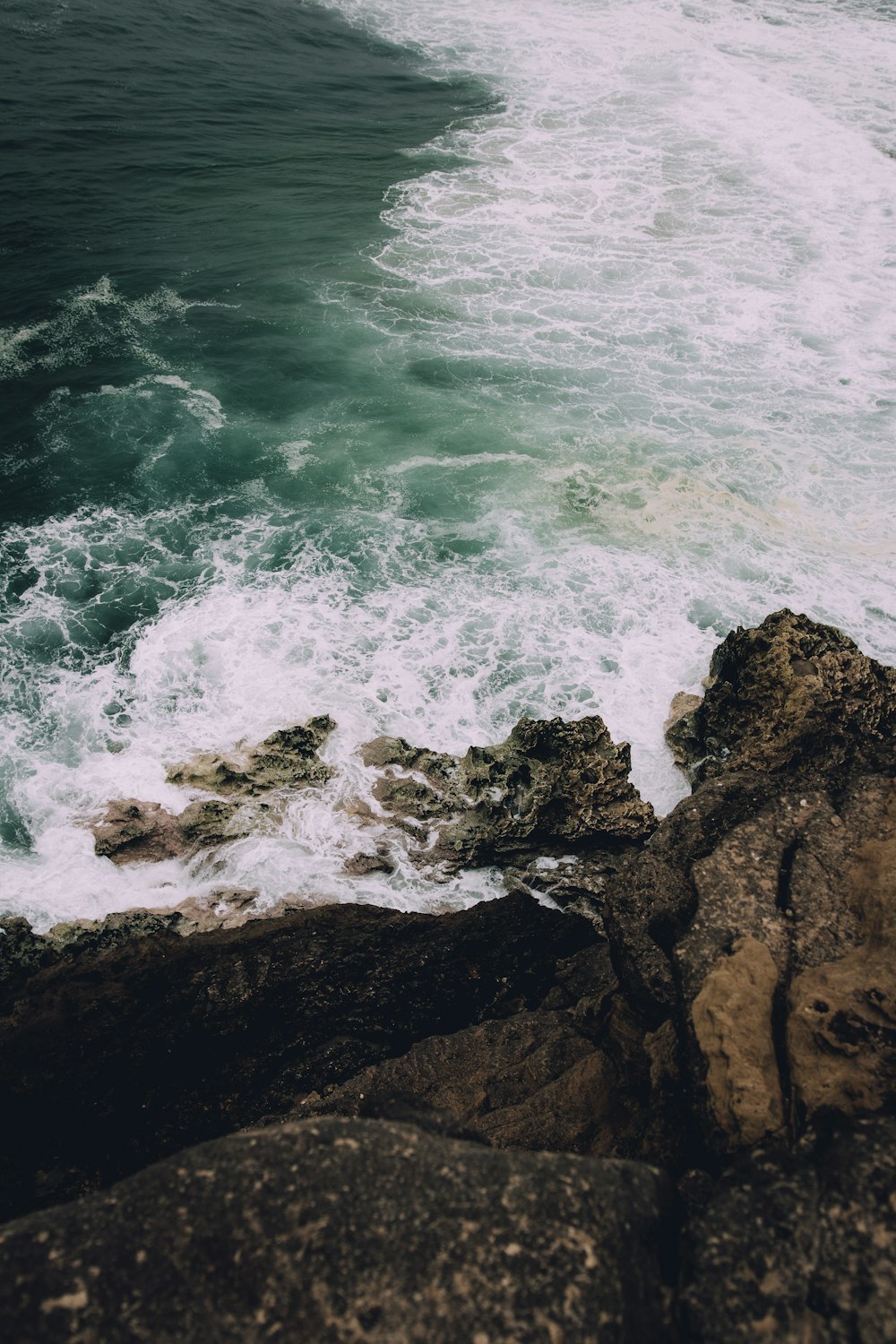 black and brown rock formation beside ocean water