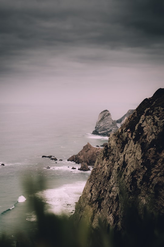 black and brown mountain range and cliff beside body of water in Cabo da Roca Portugal