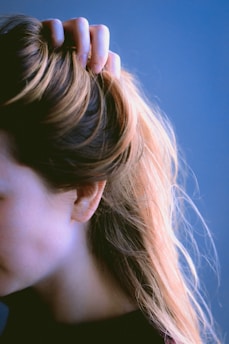 a close up of a woman's head with her hair in a pony tail