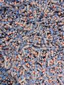 A large pile of colorful candies wrapped in white, blue, and orange packaging. The candies have illustrations and text on them, showcasing a playful and vibrant design.
