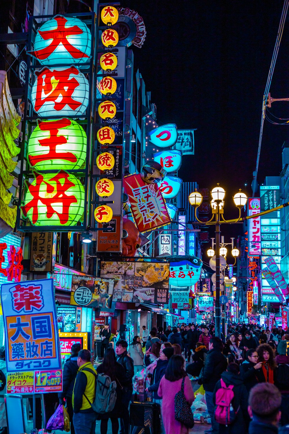 crowd walking beside buildings with neon signs