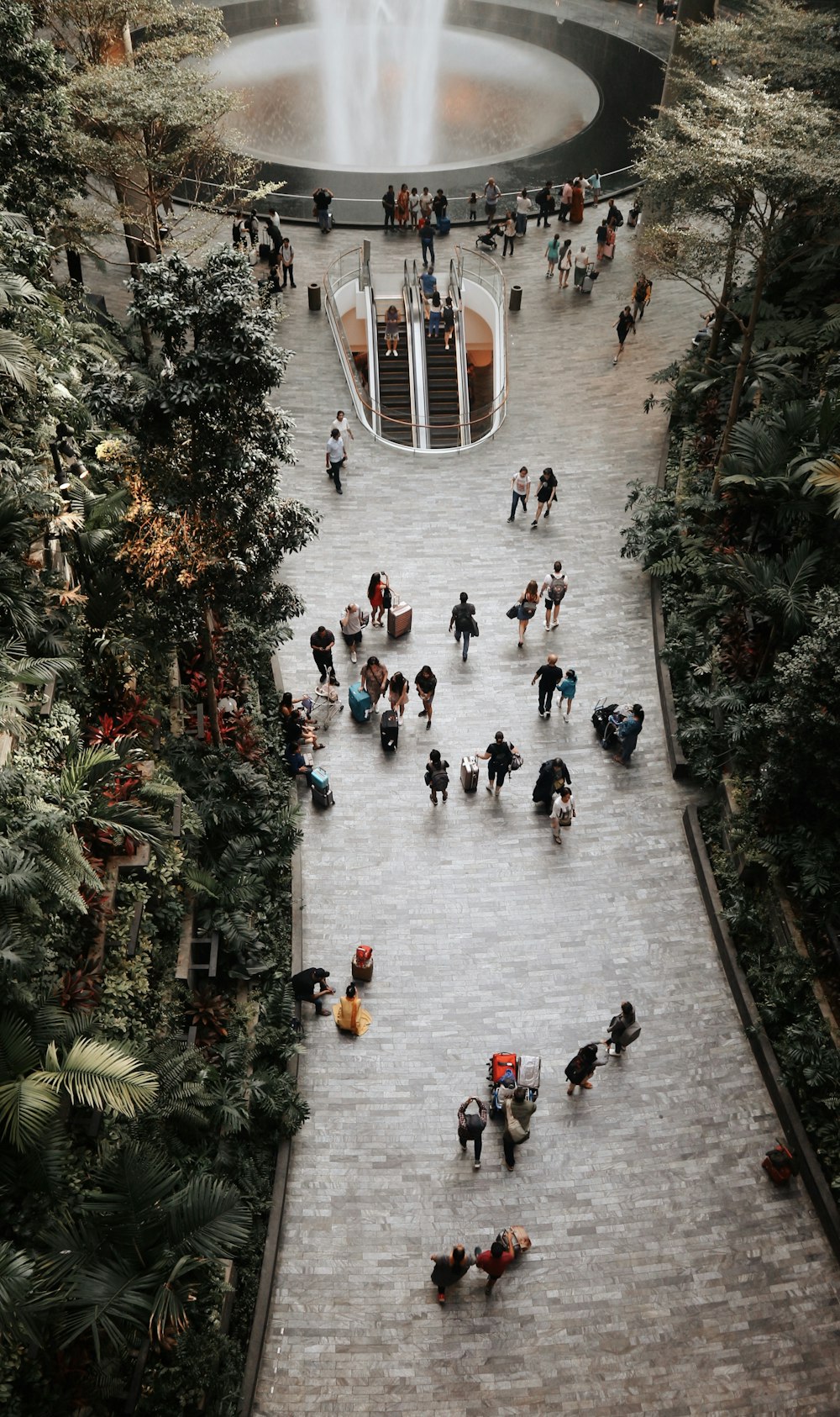 crowd walking inside airport with waterfalls