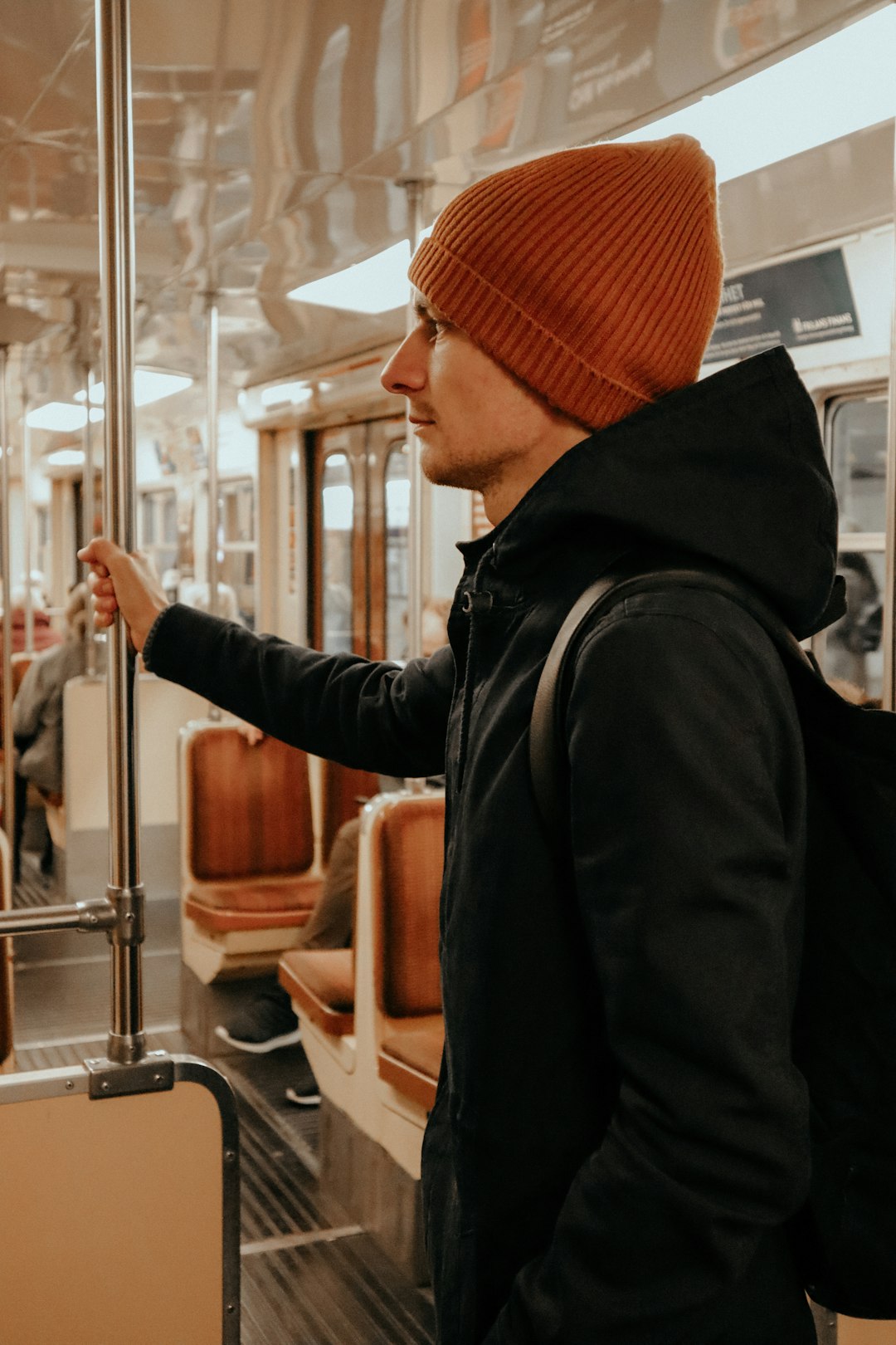 standing man holding onto train's bar