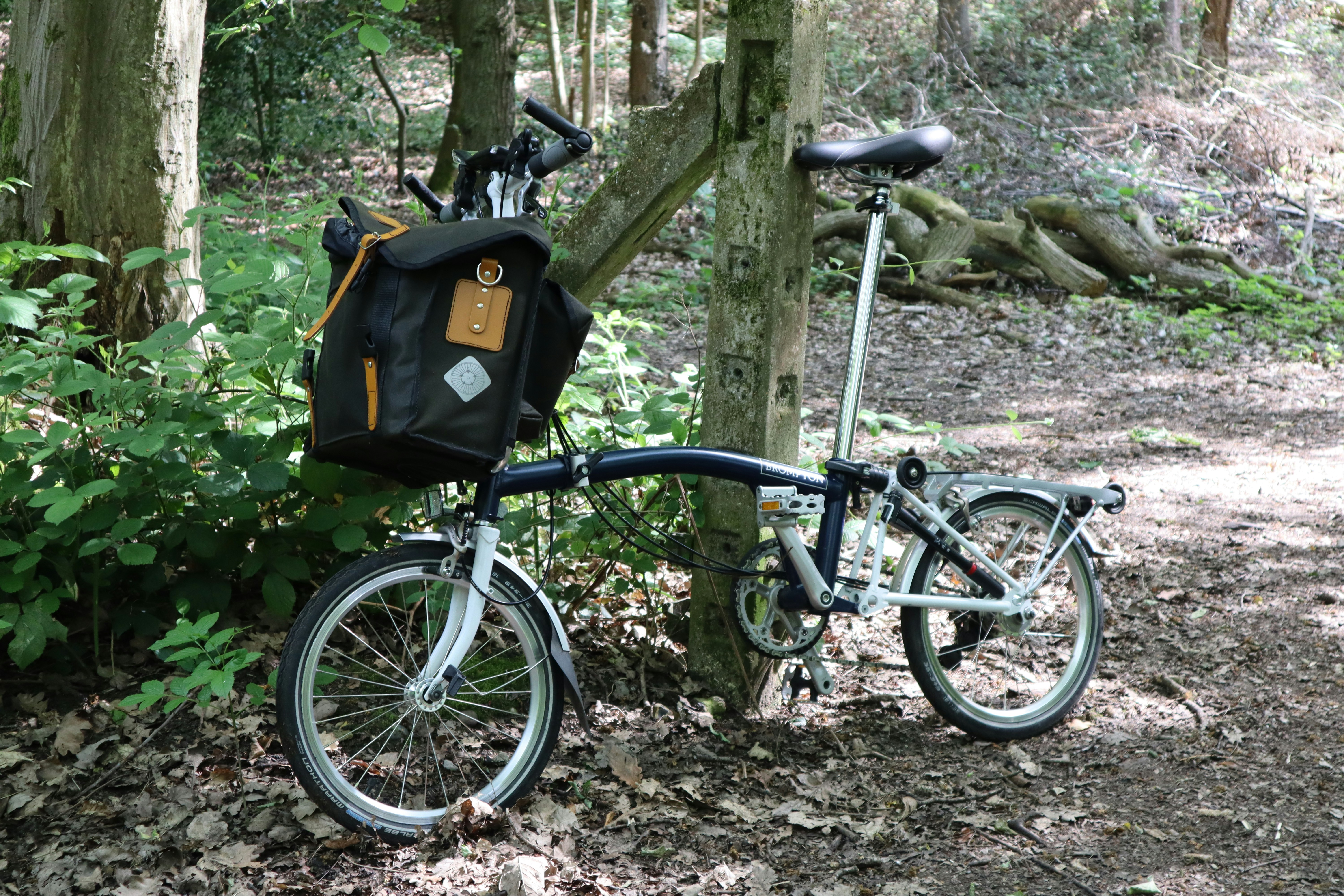 black and gray folding bike leaning on gray concrete post