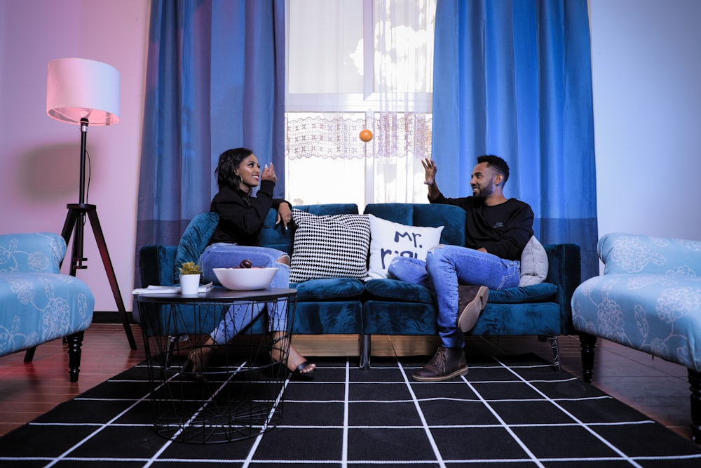 man and woman sitting on blue sofa