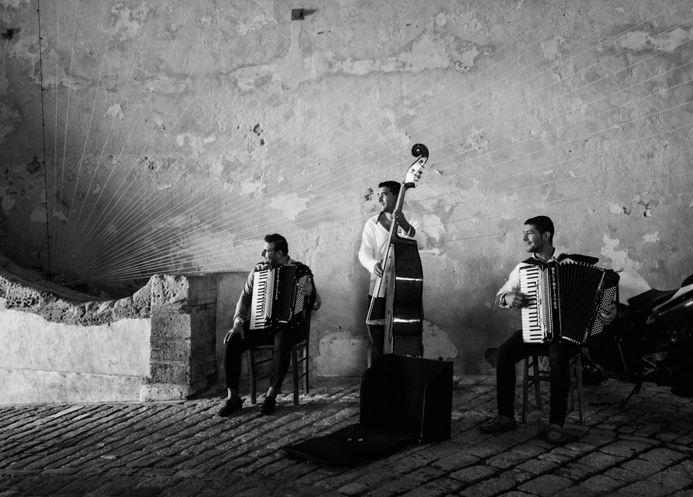 grayscale photography of three men playing musical instruments