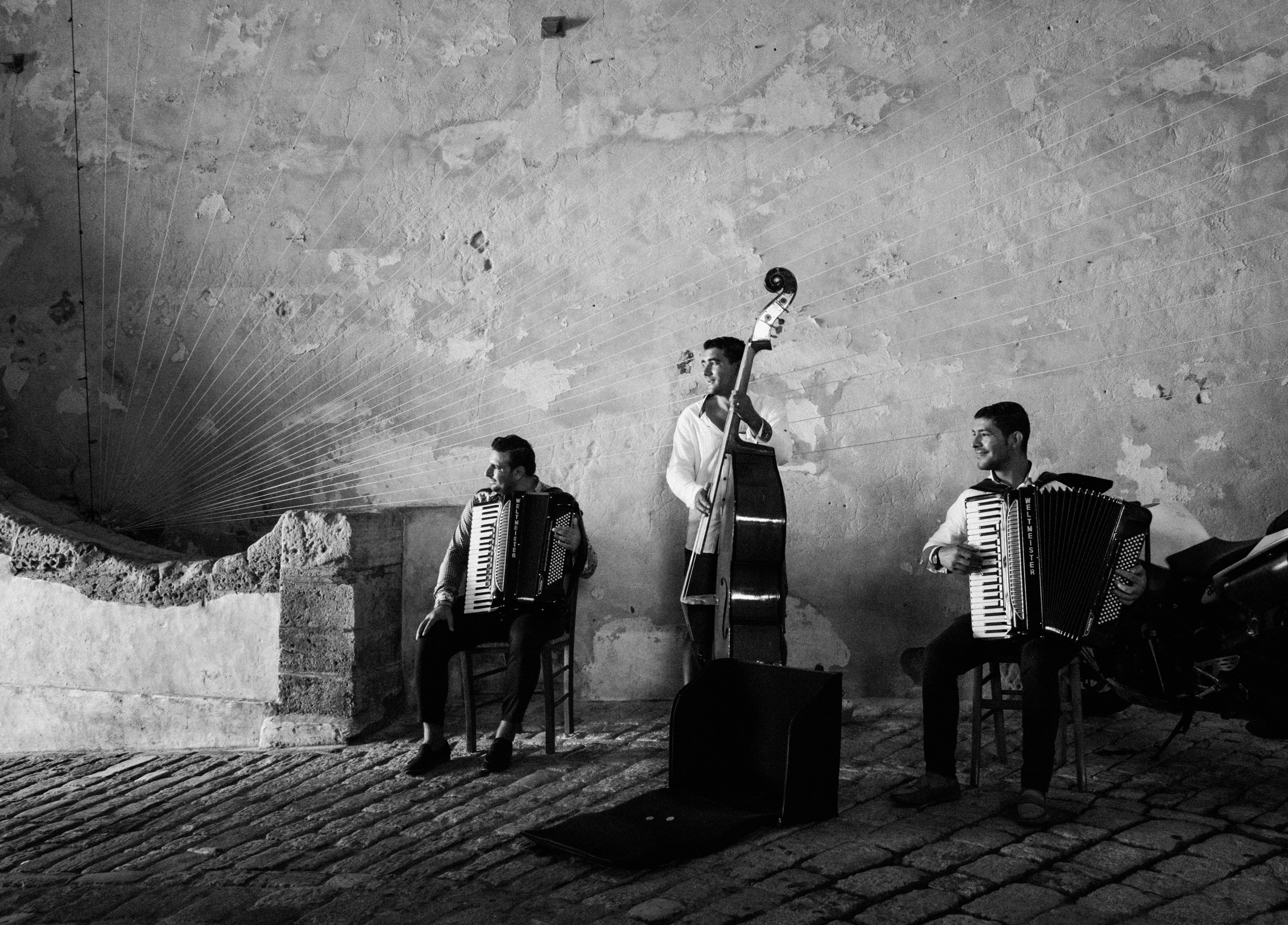 grayscale photography of three men playing musical instruments