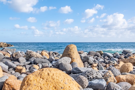 brown and gray rock formations near blue body of water under white and blue sky in La Palma Spain