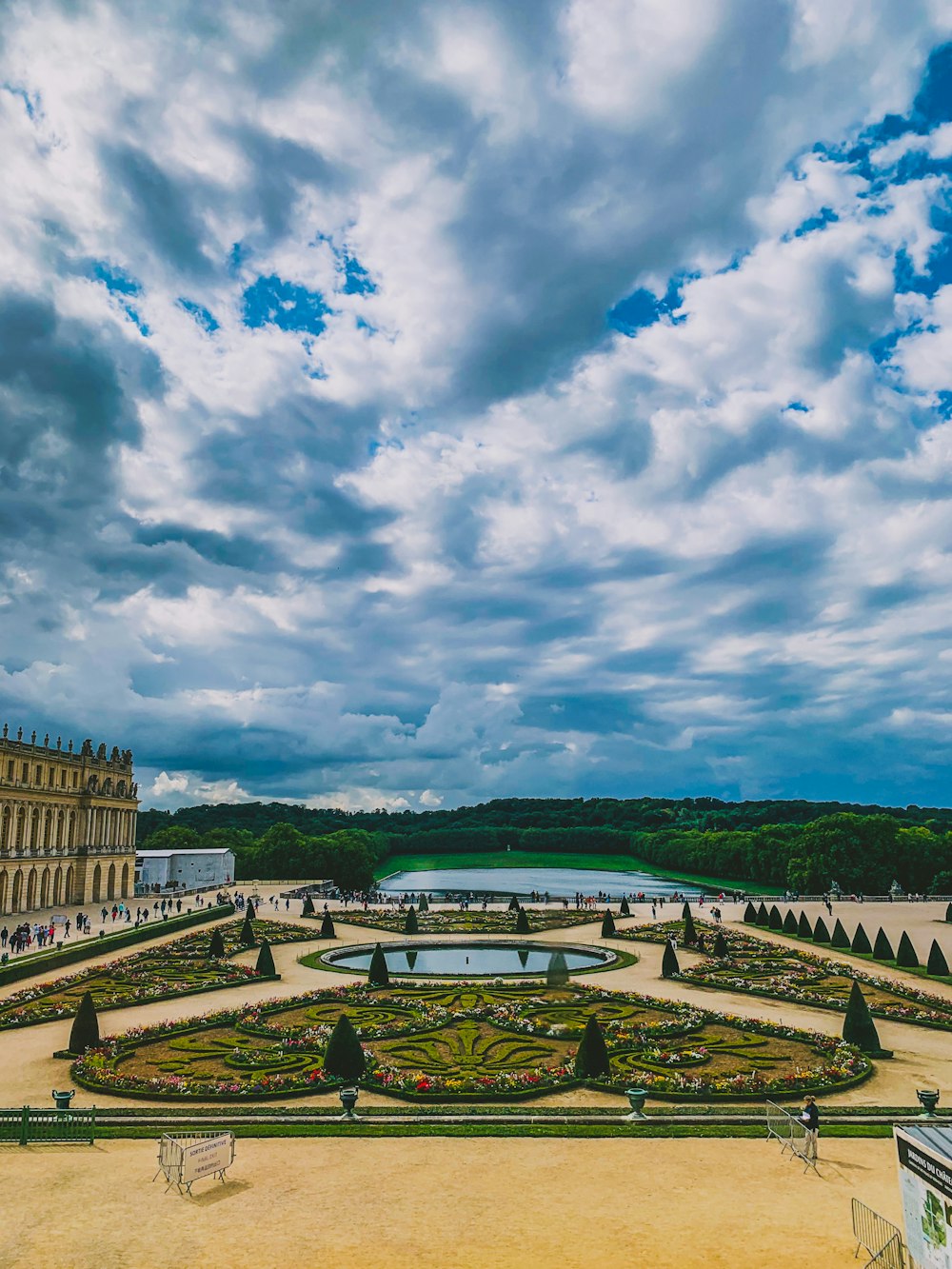 people standing near Palace of Versailles in France under white and blue sky