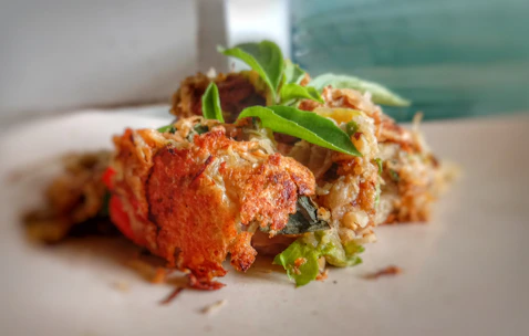 Close-up of a golden, crispy arep topped with fresh herbs and sambal.