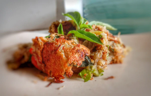 Close-up of golden, crispy gluten-free arancini on a rustic wooden board with fresh basil leaves.