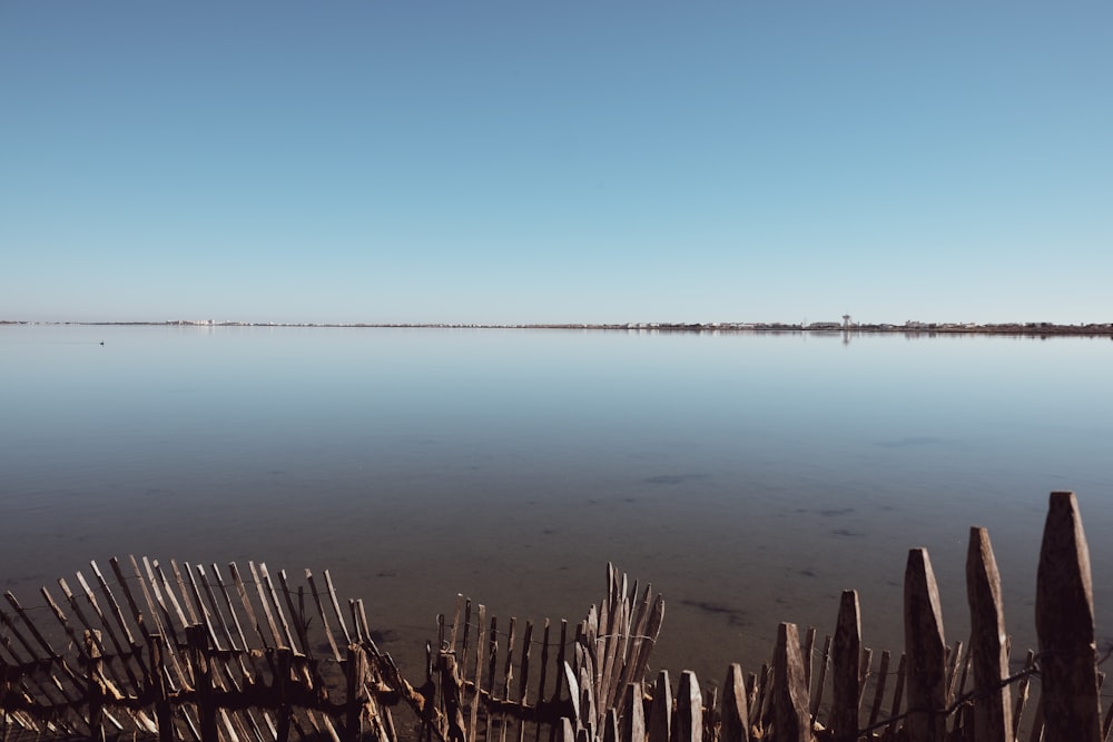 brown wooden fence near blue body of water during daytime