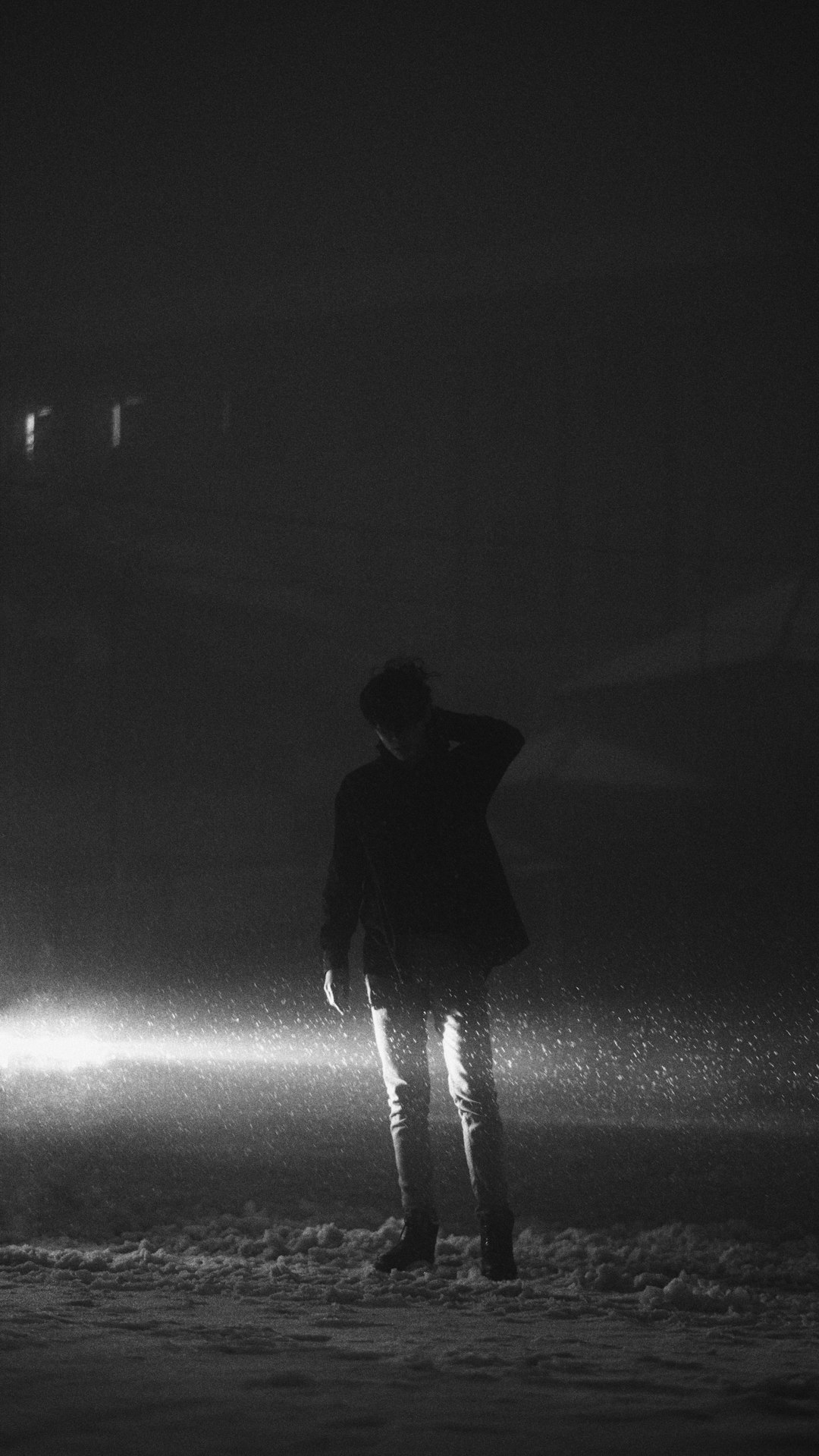 grayscale photography of man wearing jacket standing on snowy field