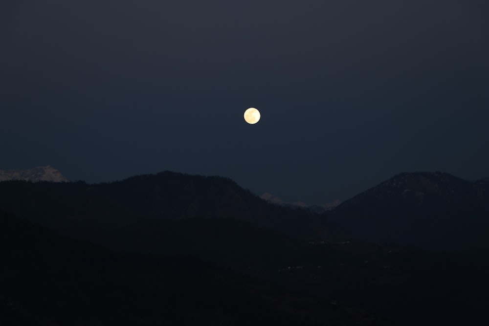 silhueta da montanha vendo a lua cheia
