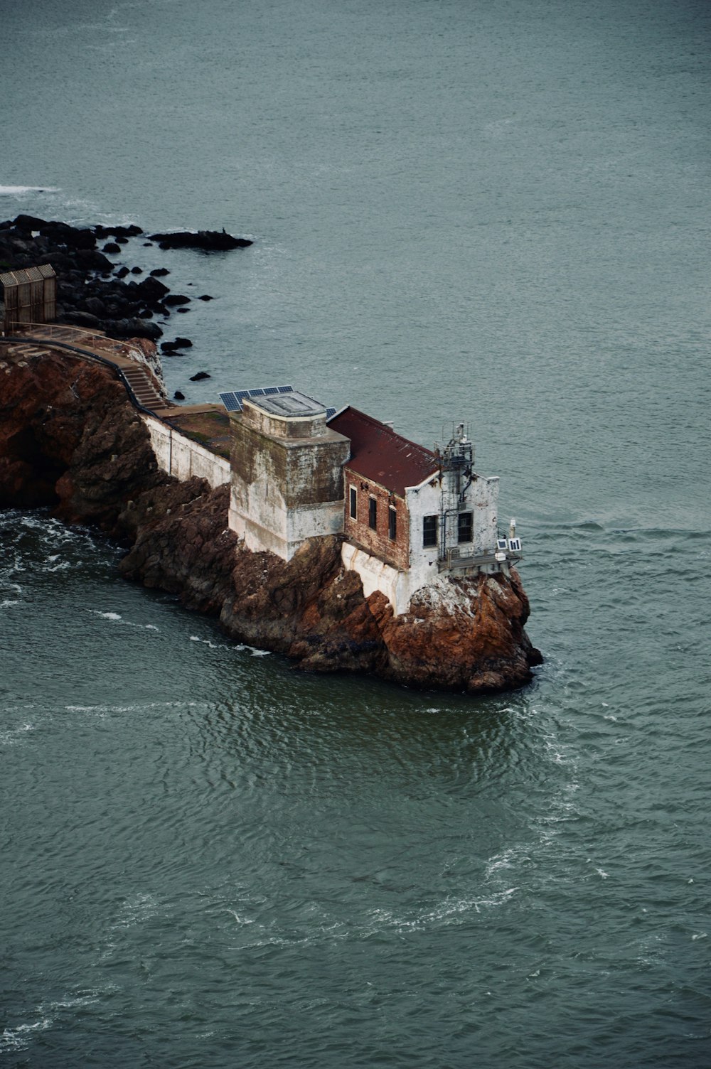 bird's eye photography of white and red concrete house on cliff near body of water